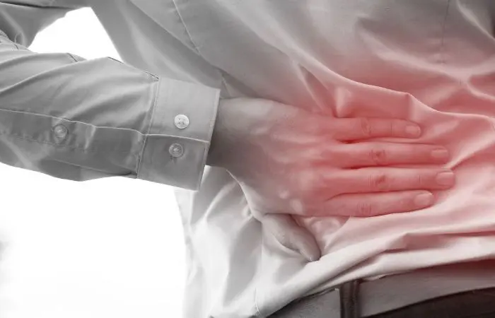 A man holding his back in pain from a fall.