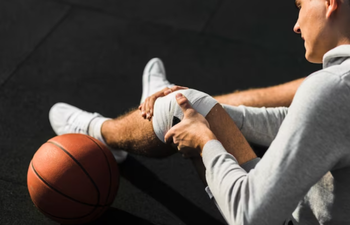 A person with their hands on the ground and another holding onto a basketball