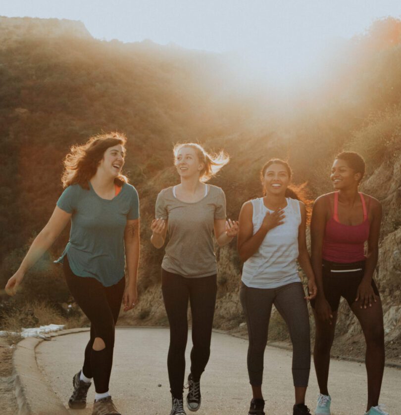 Four women are walking down a road together.